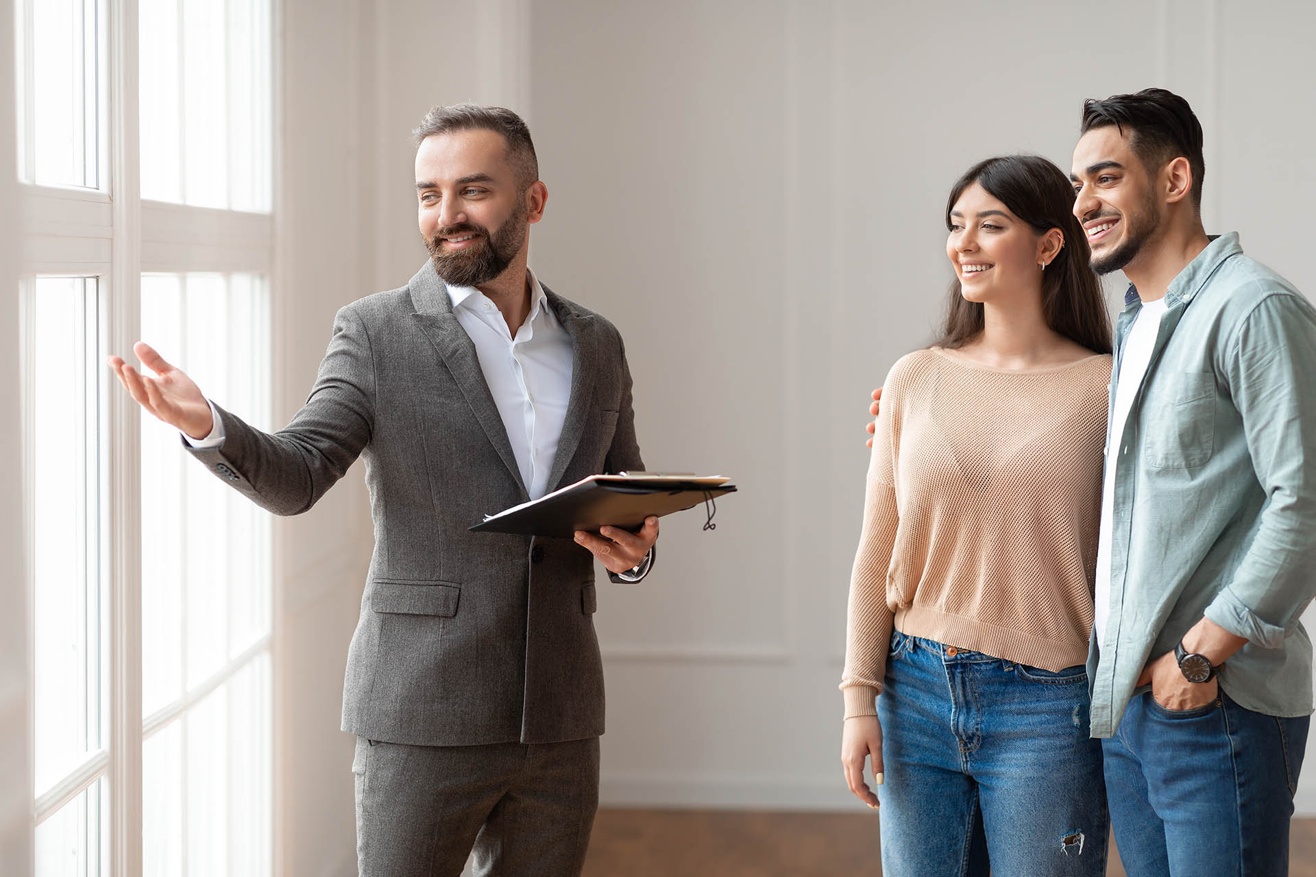 Male Realtor In Suit Showing Buyers New Apartment